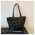 Detailed macro of black quilted nylon tote bag featuring gold metal rivet reinforcements - Black