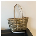 Close-up of golden quilted puffer tote bag with metallic finish and leather straps - Champagne