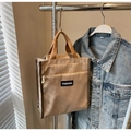 Detail of khaki canvas tote bag featuring front zipper pocket and FASHION woven label - Khaki