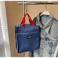 Close-up of blue canvas tote bag with red handles and front fashion zipper pocket - Blue