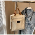 Detail of cream canvas tote bag with brown handles and FASHION label on a metal hook - Off White