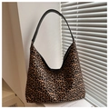 Detail einer Schultertasche mit Leopardenmuster und schwarzen Ledergriffen im Licht - Braun