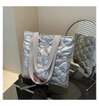 Close-up of a silver quilted puffer tote bag with metallic finish and woven handles - Silver