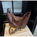 Minimalist large dark brown crescent tote bag with adjustable strap on marble surface - Coffee