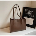 Close-up of the FASHION embossed logo on a deep brown minimalist leather tote bag - Coffee