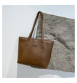 Detalle de bolso tote de cuero marrón con etiqueta FASHION sobre piedra texturizada - Marrón