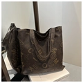 Macro detail van de bruine lederen tote bag met MOCIA letterprints en textuur - koffiekleur