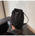 Close-up of black suede bucket bag showing drawstring closure and silver hardware details - Black