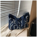 Dettaglio della borsa tote in denim blu scuro con toppa NEW YORK e bordi sfilacciati - Blu scuro
