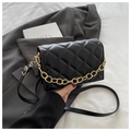 Detailed view of black quilted faux leather handbag with gold chain on a grey blazer - Black