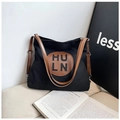Détail d'un sac hobo en toile noire avec lanières en cuir marron et logo rond - Noir