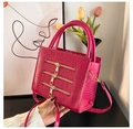 Detail of rose red crocodile embossed handbag featuring three decorative gold zippers - Rose Pink