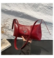 Close-up of red glossy leather baguette bag with silver star emblem and shoulder strap - Red