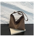 Detail of dark brown suede hobo bag with unique knot shoulder strap on artistic books - Brown