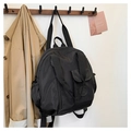 Close-up of black nylon travel bag with round embossed logo and front pocket details - Black