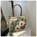 Detailed mirror view of a floral tote bag with 3D embossed flowers and woven handles - Green