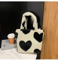 Detailed view of plush faux fur tote bag with black heart patterns on marble surface - White