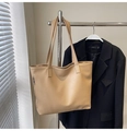 Detail of beige tote bag with litchi texture hanging next to a black blazer coat - Khaki