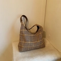 Borsa tote a quadri marroni con tracolla in pelle su una morbida coperta in pile bianco - caffè
