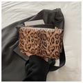 Detail showing leopard print texture and gold metal hardware on a square handbag - Brown