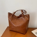 Deep brown tote bag with crocodile pattern and long straps on a wooden surface - Brown