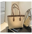 Elegante bolso tote beige con ribetes y asas en marrón oscuro en una sala minimalista - Caqui