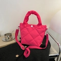 Pink quilted bucket bag with crossbody strap and top handle displayed on casual clothes - Rose Red