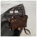 Detalle del bolso de cubo en cuero PU marrón oscuro con asa anudada y grabado fashion - café