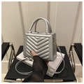 Close-up of silver quilted PU leather handbag with dual handles and golden hooks - Silver