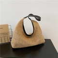 Beigefarbene Strohtasche mit schwarzen Kunstledergriffen und Besatz auf dunklem Tisch - Schwarz