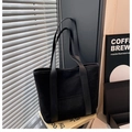 Detalle de bolso tote negro de ante con correas de cuero sobre libros en escena gris - Negro