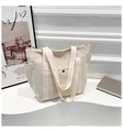 Detalle de bolso tote de lona beige con bolsillos laterales y hebilla metálica en soporte - Blanco