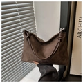 Primer plano de bolso de ante con nudos decorativos y elementos metálicos plateados - café