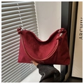 Detalle macro del bolso hobo de ante rojo oscuro con un diseño de asa con nudo circular - Rojo