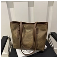 Dettaglio della grande borsa tote marrone con scritte dorate su una sedia nera - Caffè Senza Ciondolo