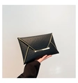 Dettaglio di una pochette a busta nera con trama a struzzo e rifiniture in metallo dorato - Nero