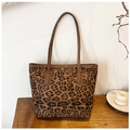Detail of large leopard print tote bag with brown leather handles on a wooden table - Leopard Brown