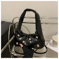 Detail einer glänzend schwarzen Lederhandtasche mit silbernen Nieten und zwei Griffen - Schwarz