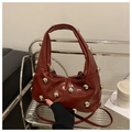 Detailansicht der weinroten Lackledertasche mit goldenen Metallkugeln und Falten - Rot