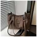 Detalle de bolso tote marrón oscuro con cadena de metal y placa de logo de moda - café