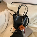 Black textured leather bucket bag with top handles and cute brown plush puppy charm - Black With Pendant