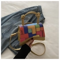 Macro detail of geometric patchwork mini bag with curved base and gold chain strap - Gold