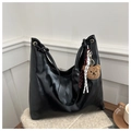 Detail of black leather tote bag with a cute plush bear charm on white knit texture - Black With Pendant