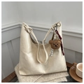 Detail of cream white leather hobo bag featuring a knotted strap and cute bear charm - White With Pendant