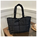 Detailed view of the black quilted tote bag with magnetic snap button and soft fabric texture - Black