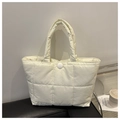 Detail of cream quilted tote bag with glossy finish and snap button closure on leather base - White