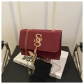 Detalle del bolso cuadrado de ante burdeos con logo dorado hueco y cadena con borla - Rojo