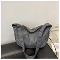 Detalle del bolso de lona gris oscuro en forma de media luna sobre un sofá - Gris