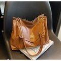Bruine leren vintage tote tas met gouden ketting en metalen slot op een leren stoel - Bruin