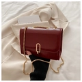 Detail view of burgundy crossbody bag with gold metal lock and chain on elegant background - Red